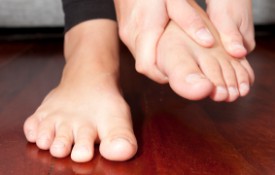 A woman rubs her aching feet on the sofa